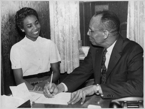 Black and white photo of two persons at a desk