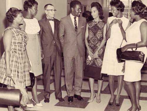 Sepia photo of seven persons posing standing up