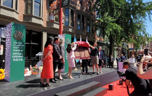 Group of people unveiling a commemorative plaque during an outdoors event in a city street