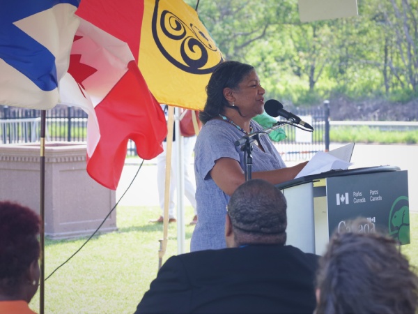 A women speaking in a microphone at an outdoor event