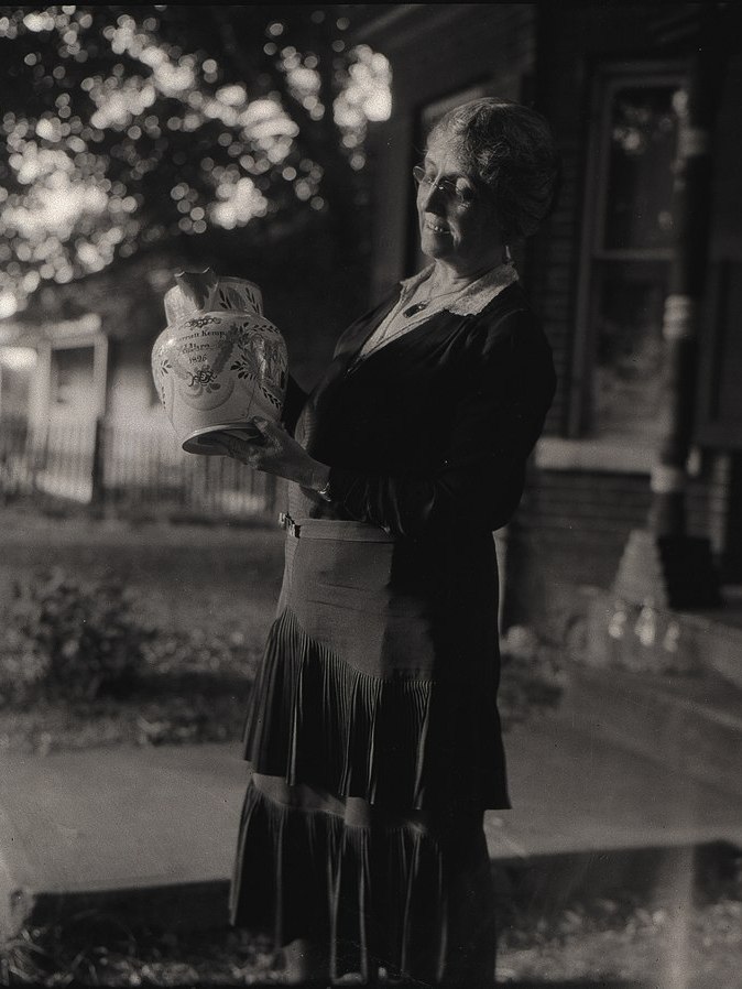 Black and white photo of a person holding a vase in an outdoor setting