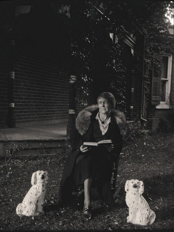 Black and white photo of a person seated and holding a book in their hands