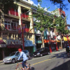 A street of a chinatown, buildings, cars, pedestrians and people biking