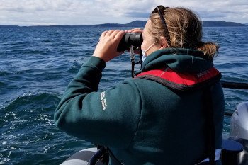 A woman in a Parks Canada jacket holding binoculars.