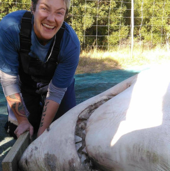 .A woman standing beside a dead shark.