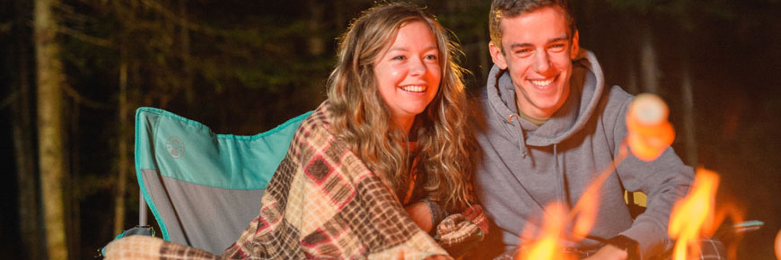 Visitors roasting marshmallows over the firepit at South Kouchibouguac Campground, Kouchibouguac National Park