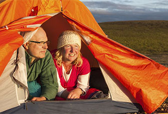 A woman sitting in her tent, looking out at a group of nearby tents.