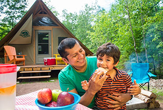 A father and son eating s’mores at an oTENTik in Cheticamp Campground.