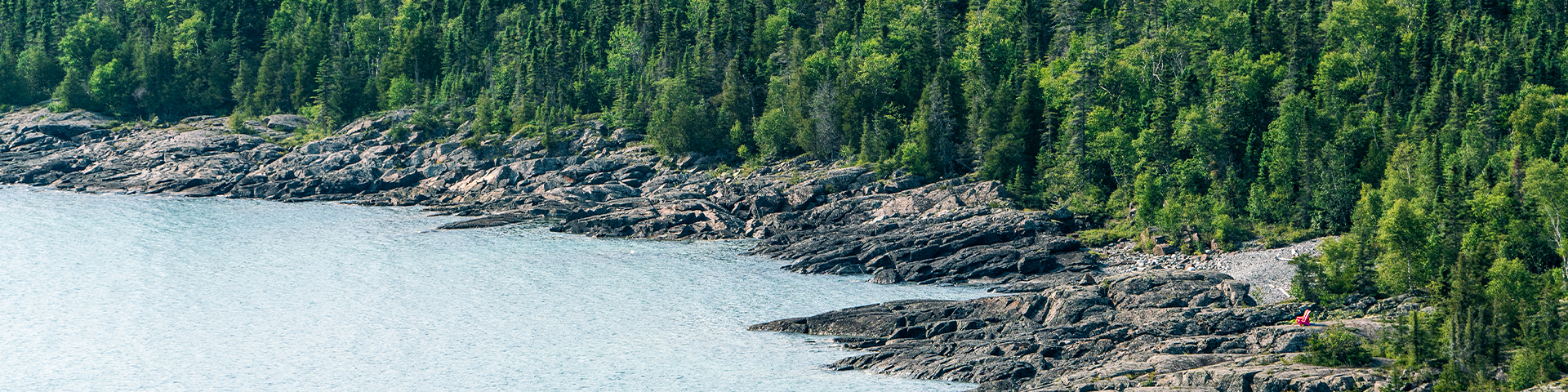 A rocky shoreline with two red chairs visible.