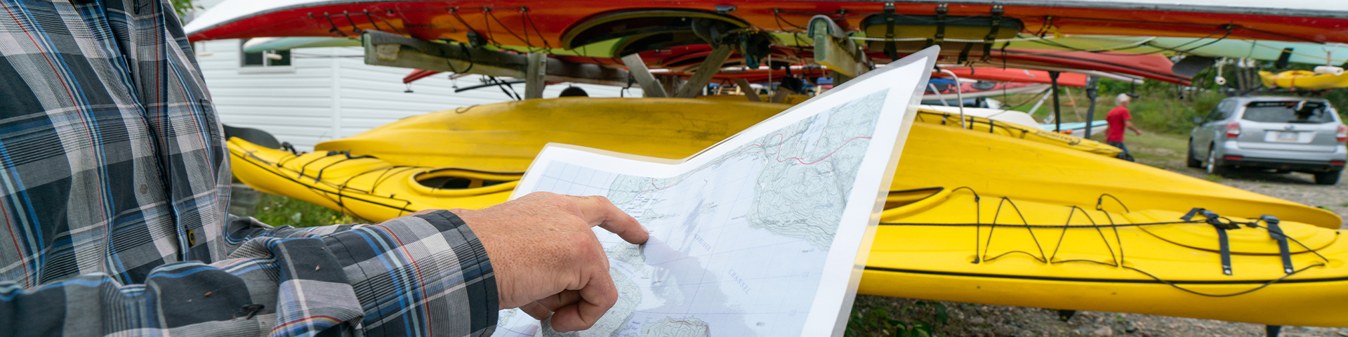 A person looking at a map near a kayak.