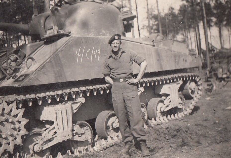 A man standing beside an armoured combat vehicle.