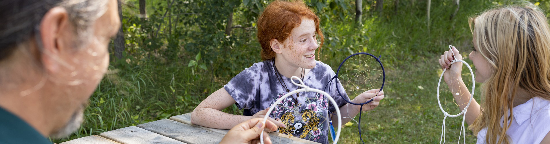 Making dream catchers on a picnic table at Rocky Mountain House National Historic Site.