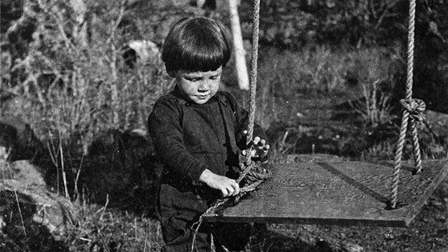 A small child holds a swing, circa 1914.