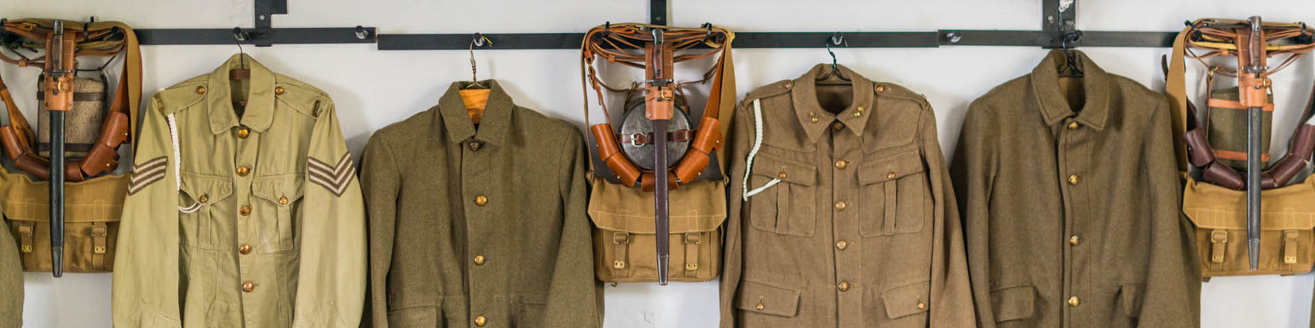 Military uniforms from WWI hung on a wall.