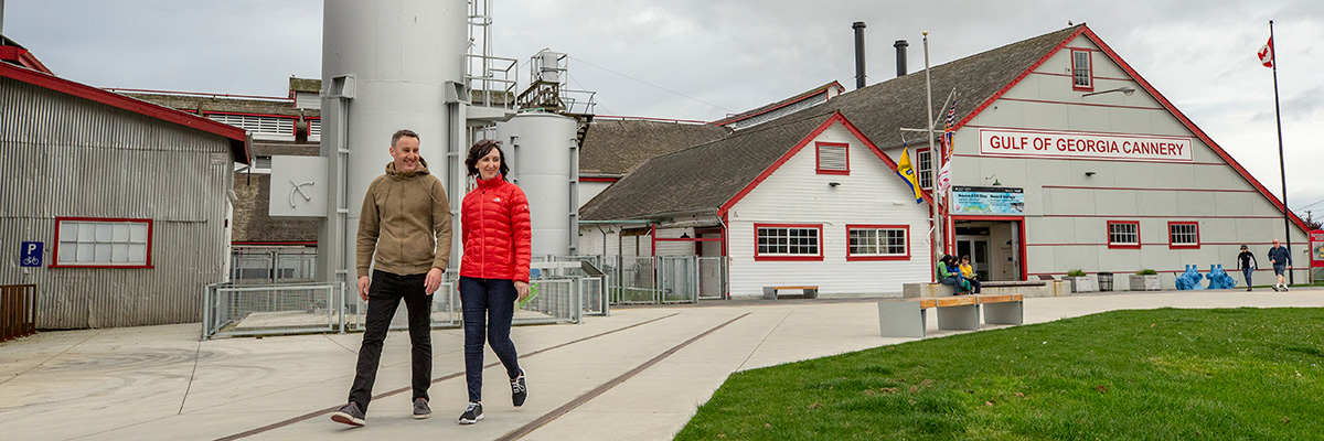 Couple walking on dike path in front of Cannery