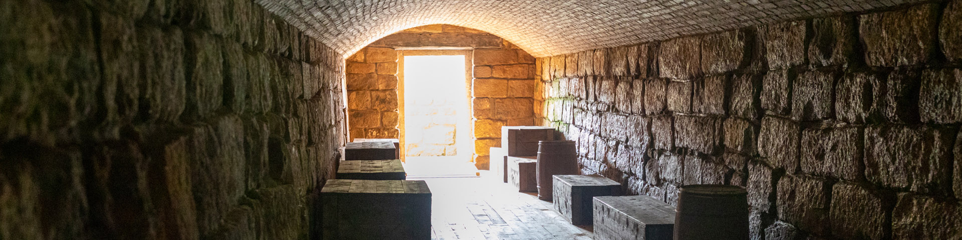 The interior of a tunnel, with wood floor, brick walls and curved ceiling.