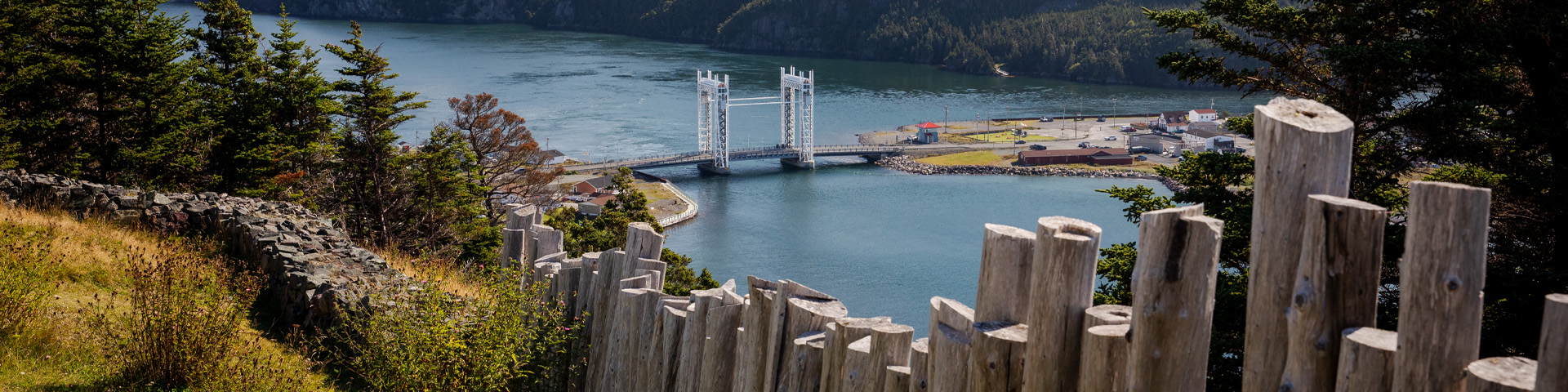 close-up of a wooden fence overlooking an ocean view with a large bridge