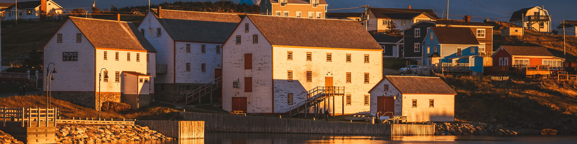 four white buildings with red trim, on the coastline