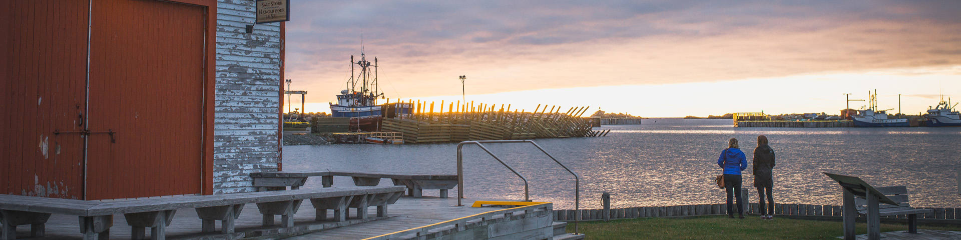 two girls looking out over a small harbour at sunrise