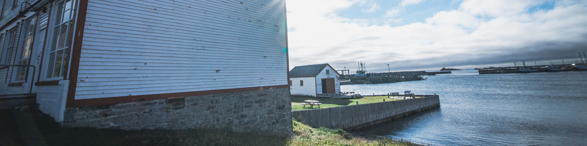 close-up of a white, wooden building with a coastal view in the background