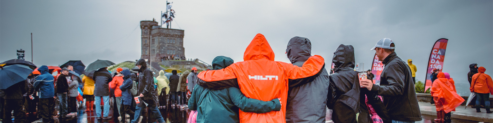 crowd of people gathered in front of Cabot Tower in the rain