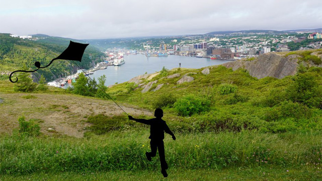 a silhouette of a child flying a kite overlooking the city