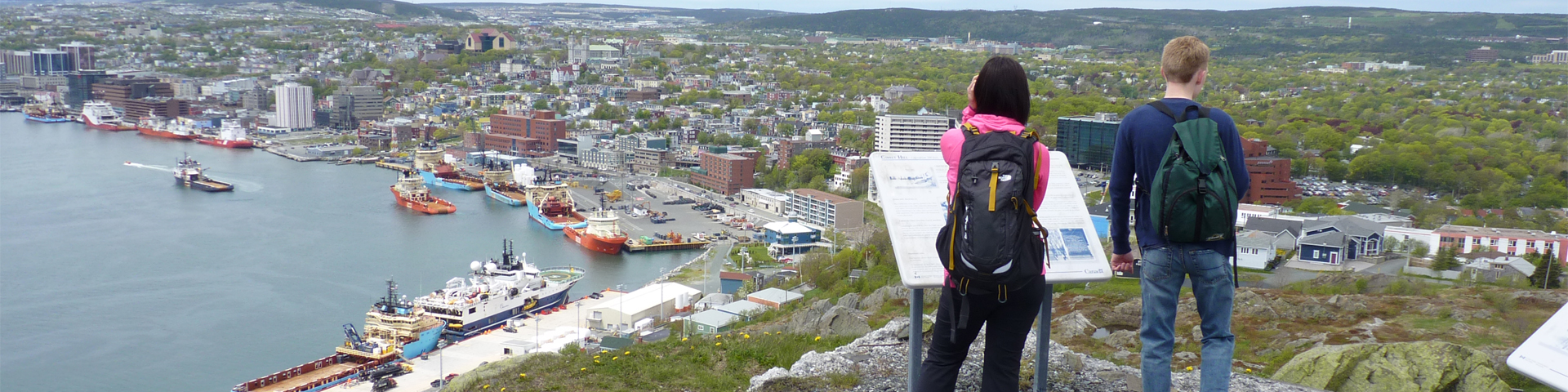 a man and a woman reading an information panel at the top of a hill