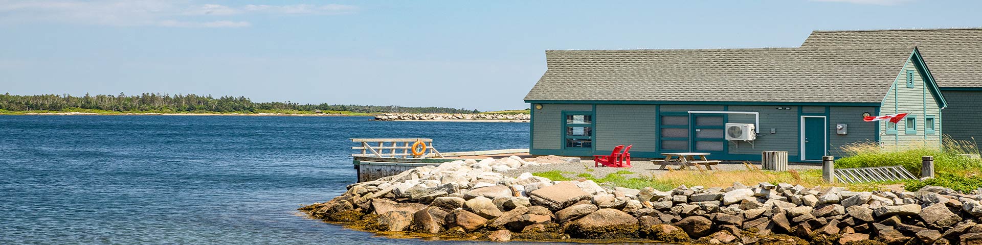 Two green buildings and a dock on the ocean