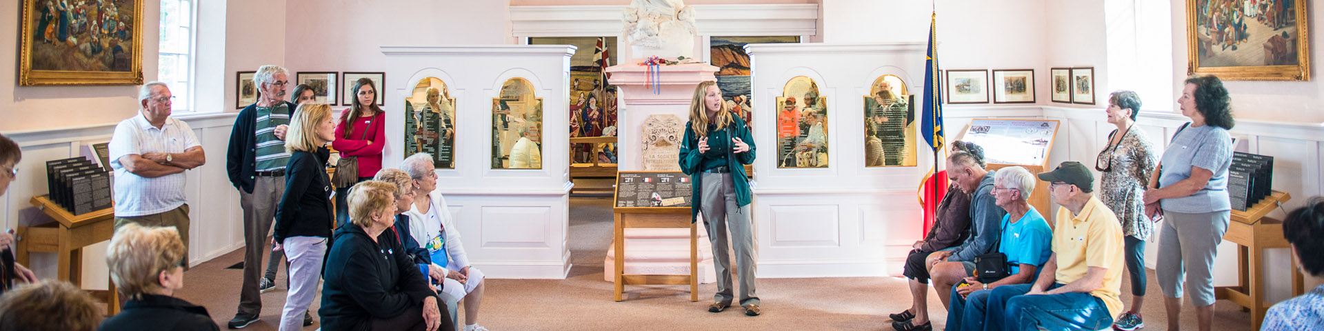 Une interprète de Parcs Canada parle à un groupe de visiteurs à l'intérieur de l'Église-souvenir.