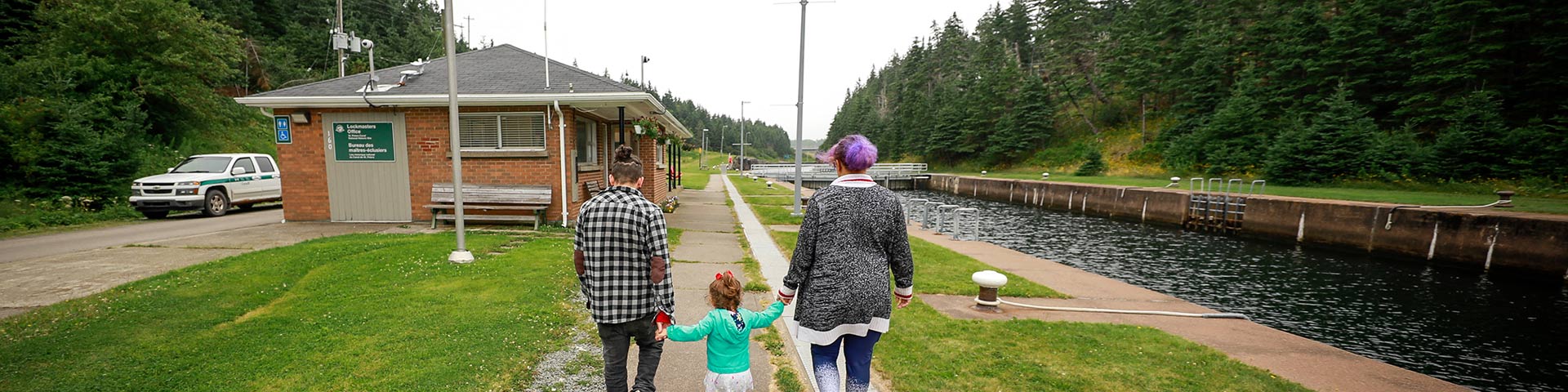 A young family of three walks beside the canal