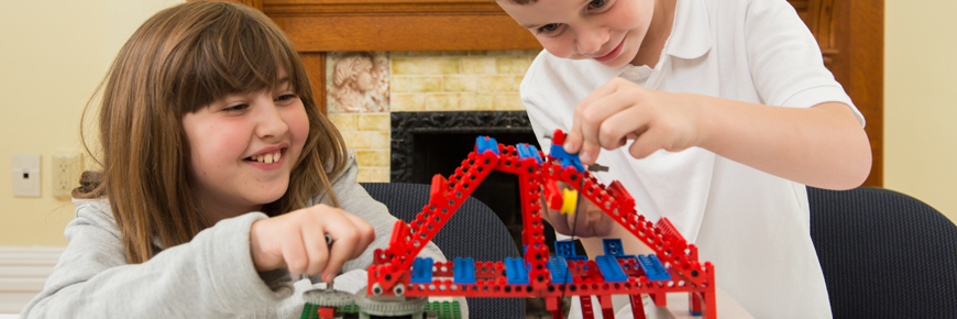 Two children playing with a model bridge.