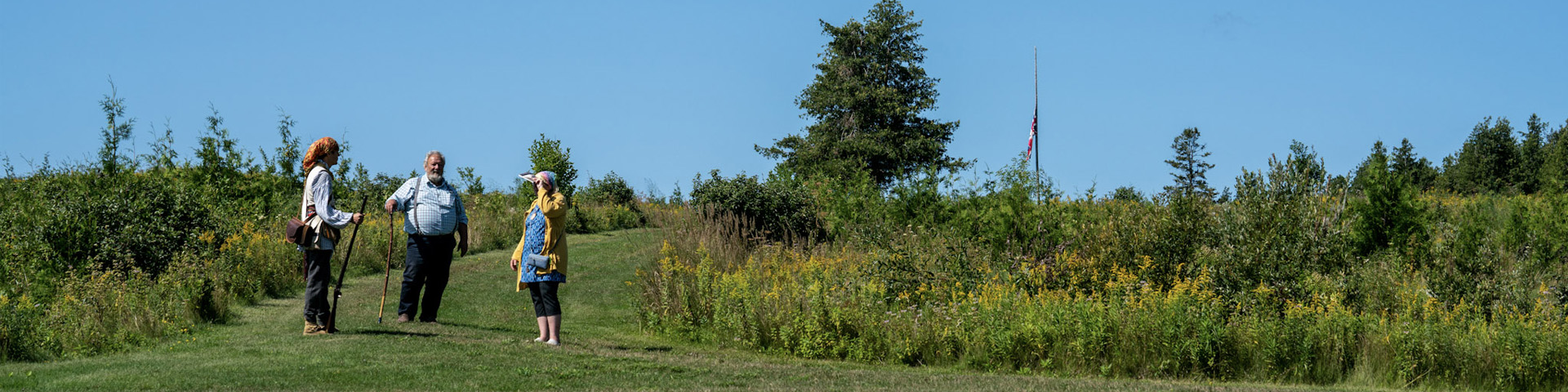 People standing on a trail through long grass.