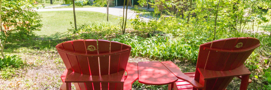 Two Parks Canada red chairs, with a view of the path to the historic home