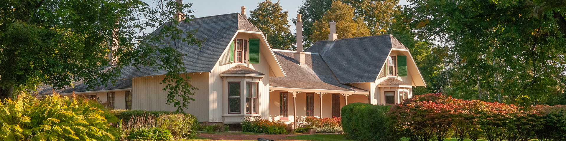 Ardgowan historic home sits amongst many green trees.  Sun is shining on the house in the early morning. 