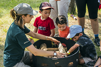 Membre de l'équipe de Parcs Canada, expliquant à allumer un feu de camps à un groupe d'enfants.