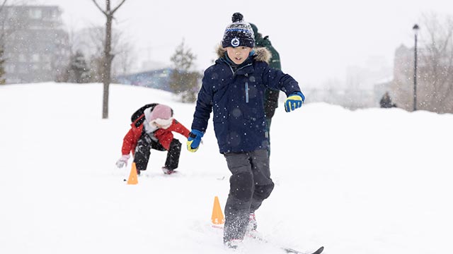 Young boy for first time with cross-country skis on fresh snow falls in winter