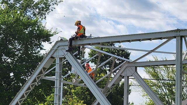 Employee climbing on bridge structure.