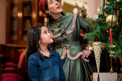 A little girl and a costumed guide contemplate an old-fashioned Christmas tree at the Sir George-Étienne Cartier National Historic Site.