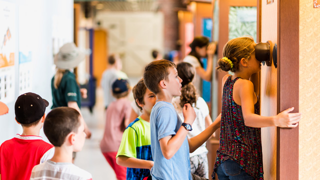  A group of elementary school students waiting in line to watch in a picture viewer.