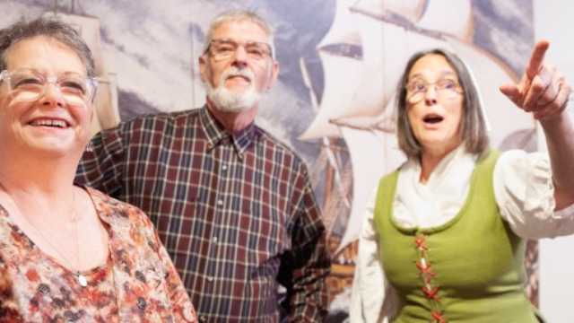 Two visitors are interacting with a costumed interpreter