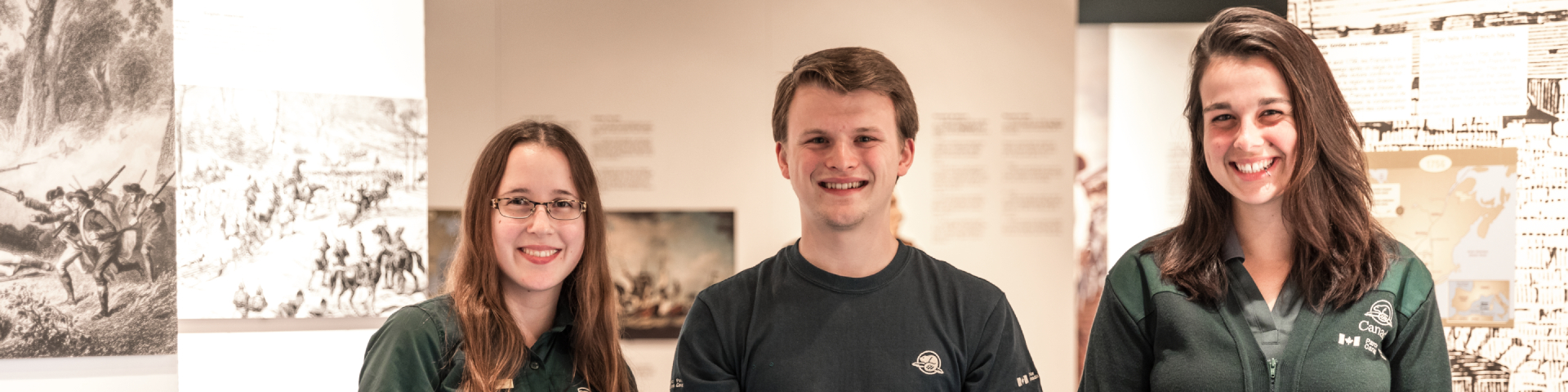 Trois employés dans une exposition sourient à la caméra. 