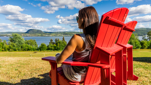 Une femme assise dans une chaise rouge admire la vue. 