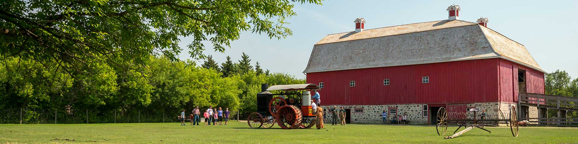 Vue de loin d'un groupe de personnes s'approchant du tracteur Hart-Parr dans l'enclos près de la grange du lieu historique national du Homestead-Motherwell