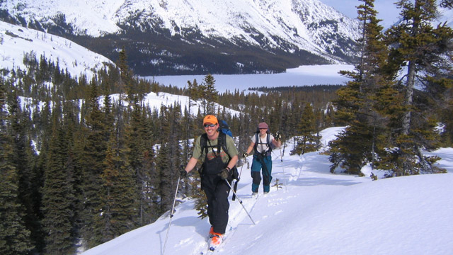 Two happy skiers in climbing a hill.