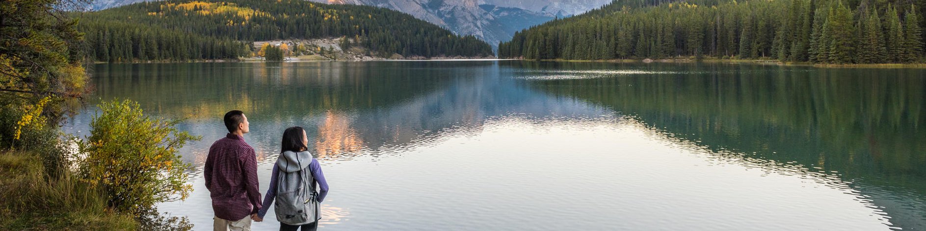 Par un matin d'automne, un couple profite de la vue panoramique du lac Two Jack, alors que le soleil se lève au camping du lac Two Jack (bord du lac). Parc national Banff. 