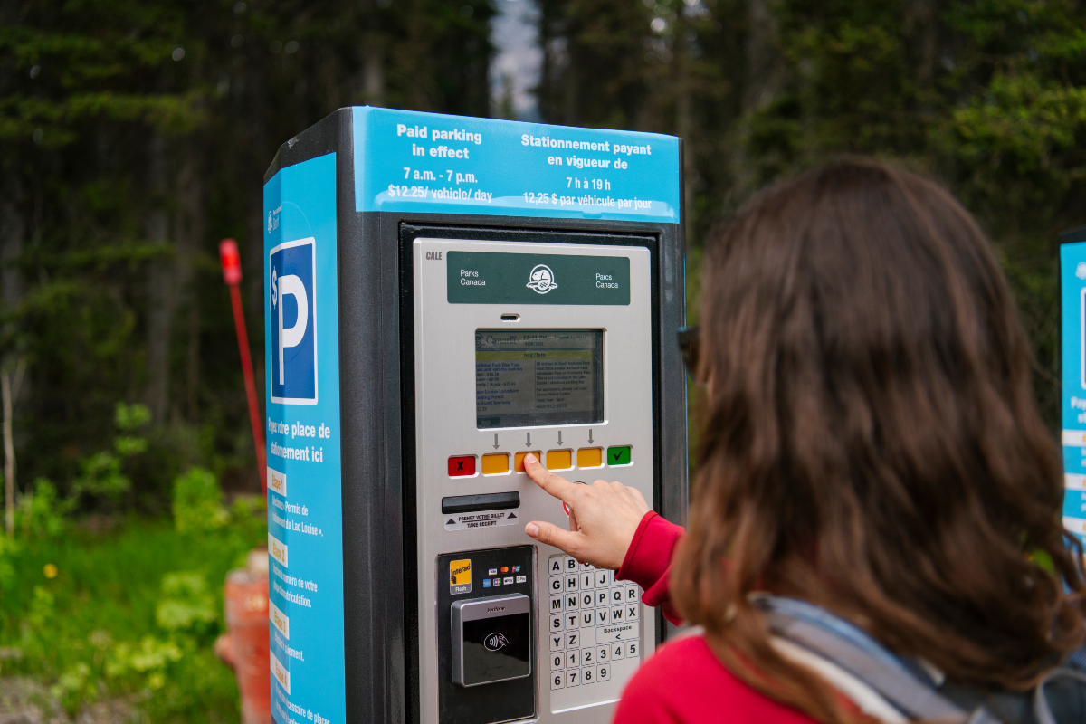 A visitor presses a button on a pay parking terminal.