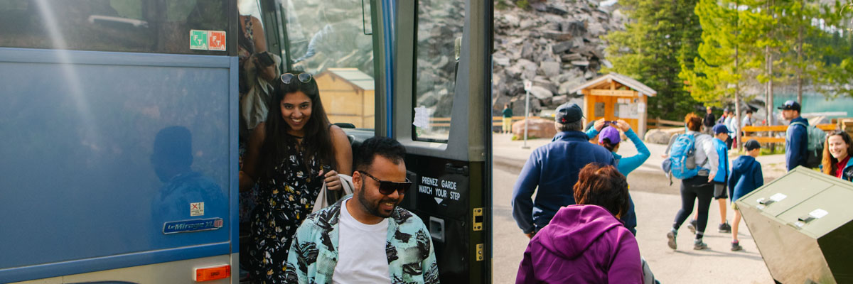 A family exits the front of a Parks Canada shuttle bus at Moraine Lake 