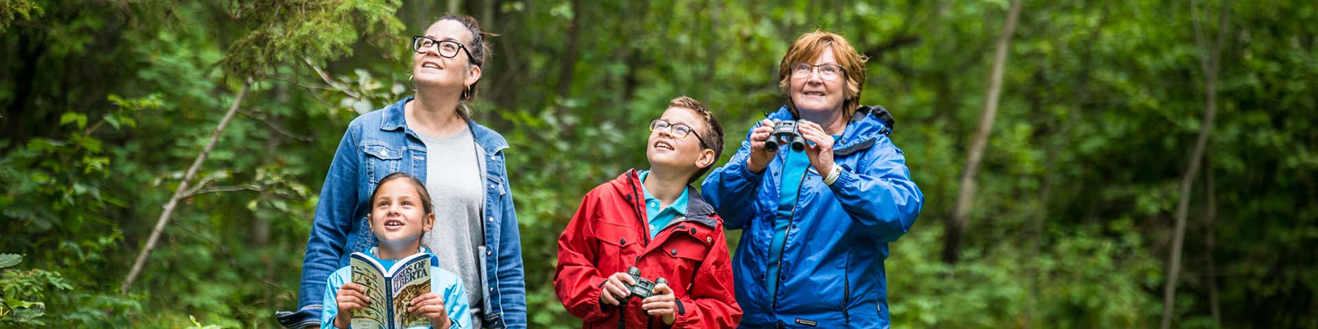 A family looks for birds in the Astotin Lake Day Use Area, Elk Island National Park.