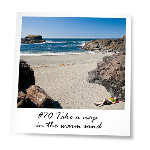 Woman lying in the sand on the beach with rock formations and blue sky