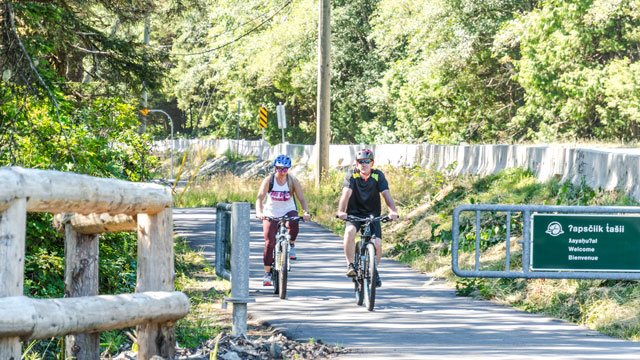 Two Cyclists on the ʔapsčiik t̓ašii with welcome sign